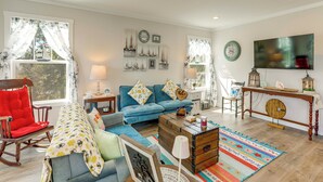 A living room with a blue sofa, a rocking chair, a wooden chest, and a colorful rug.