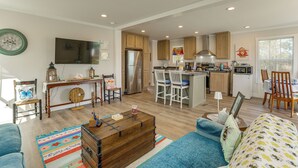 A spacious living area with a sofa, coffee table, and a kitchen with a refrigerator, stove, and dining area.