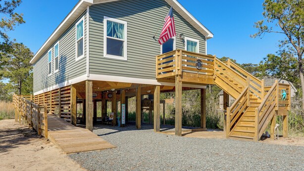 A two-story house with a wooden deck and a staircase leading to a covered porch.