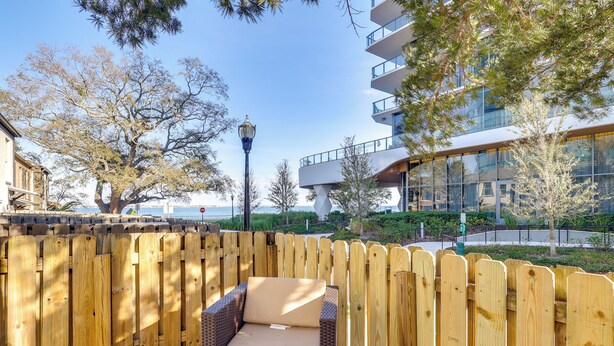 A wooden deck with a wicker chair and a wooden fence. - Water View! Walkable Gem Near Bayshore Boulevard (Tampa)