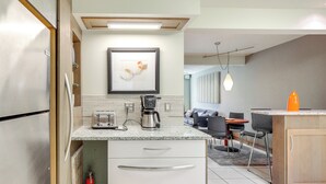 A modern kitchen with a stainless steel refrigerator, a coffee maker, and a framed artwork on the wall. - Water View! Walkable Gem Near Bayshore Boulevard (Tampa)