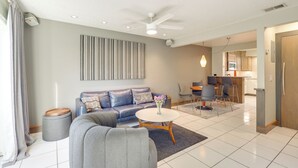A modern living room with a sofa, coffee table, and a dining area with chairs and a table. - Water View! Walkable Gem Near Bayshore Boulevard (Tampa)