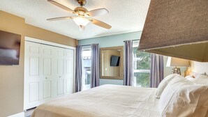 A hotel bedroom with a large bed, a ceiling fan, a flat-screen TV, and a window with curtains. - Water View! Walkable Gem Near Bayshore Boulevard (Tampa)