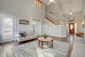 A spacious living room with a staircase, a round coffee table, and a white sofa. - Private Yard & Pool Access! Family Home in Acworth (Acworth)