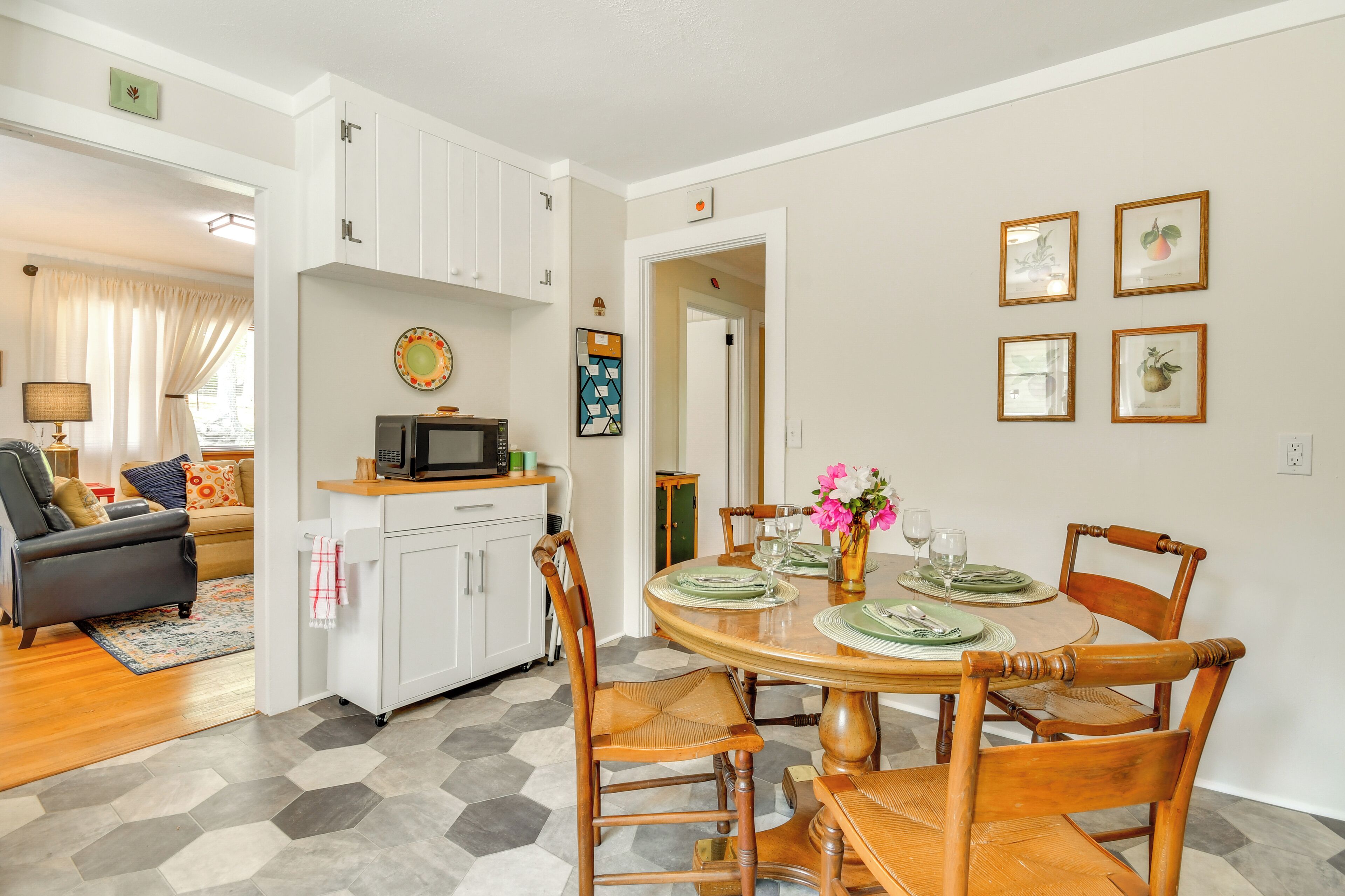 A dining area with a round table, chairs, and a kitchen in the background.