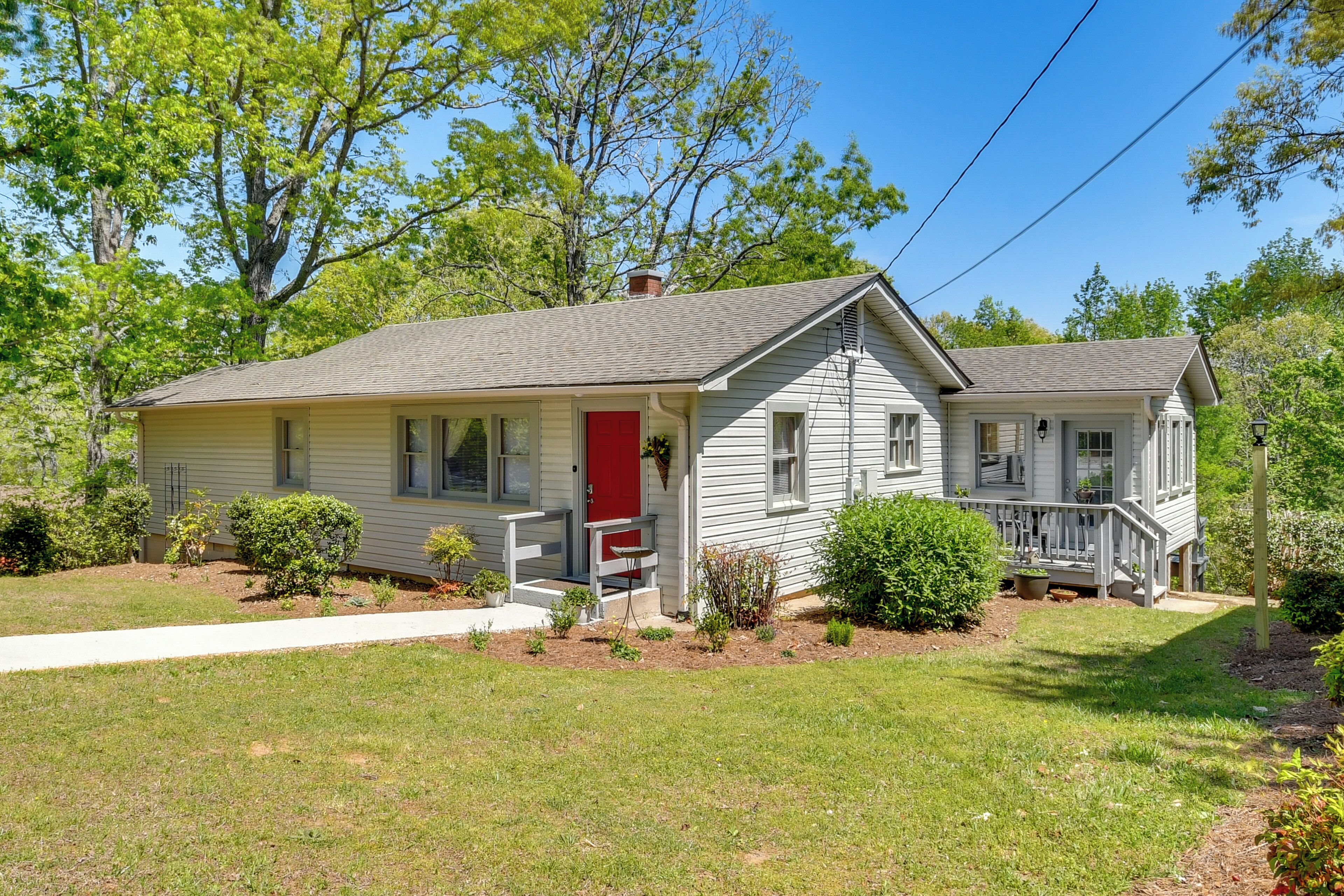 A single-story house with a front porch, a red door, and a small front yard.