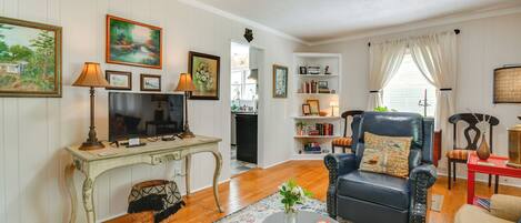 Una sala de estar con televisor, sofá, mesa de centro y estantería.