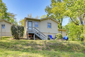 A two-story house with a front porch, a staircase leading to the entrance, and a small outdoor seating area with blue chairs. - Near Horse Shows & Events! Blissful Tryon Cottage (Tryon)