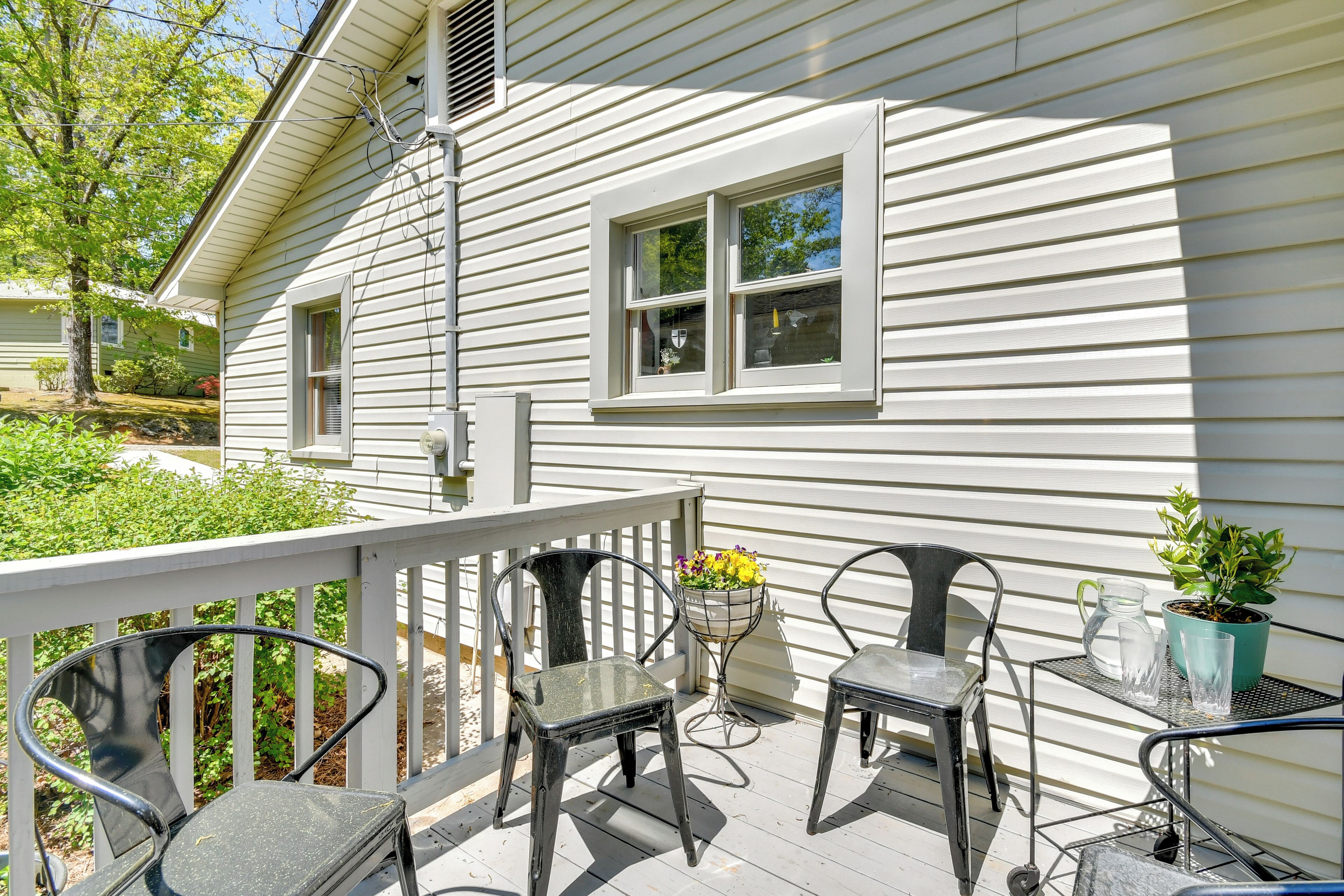 A porch with metal chairs, a small table, and a potted plant.