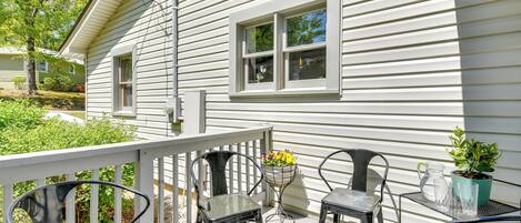 A porch with metal chairs, a small table, and a potted plant.
