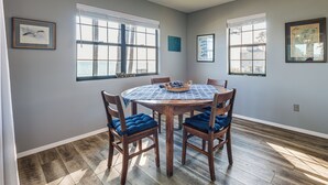 A dining area with a round table, four chairs, and a window with a view. - Gwynn's Island Gem Private Beach & Bay Views (Gwynn)
