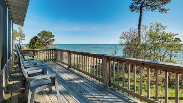 A wooden deck with chairs, a railing, and a view of the water. - Gwynn's Island Gem Private Beach & Bay Views (Gwynn)