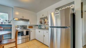 A modern kitchen with stainless steel appliances, white cabinetry, and a tiled floor. - Near Ocean & Redwood National Park! Home w/ Yard (Crescent City)