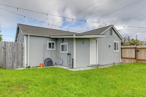 Une maison de plain-pied à l’extérieur gris, avec une porte blanche et un petit porche.