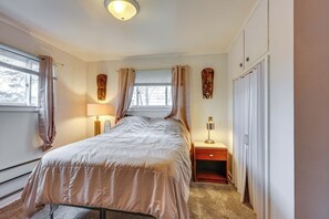 Une chambre à coucher avec un lit, des rideaux, une table de chevet, une lampe et une armoire.