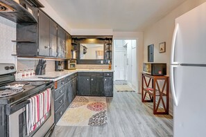 Une cuisine avec des meubles de rangement de couleur sombre, une cuisinière, un four à micro-ondes et un réfrigérateur.