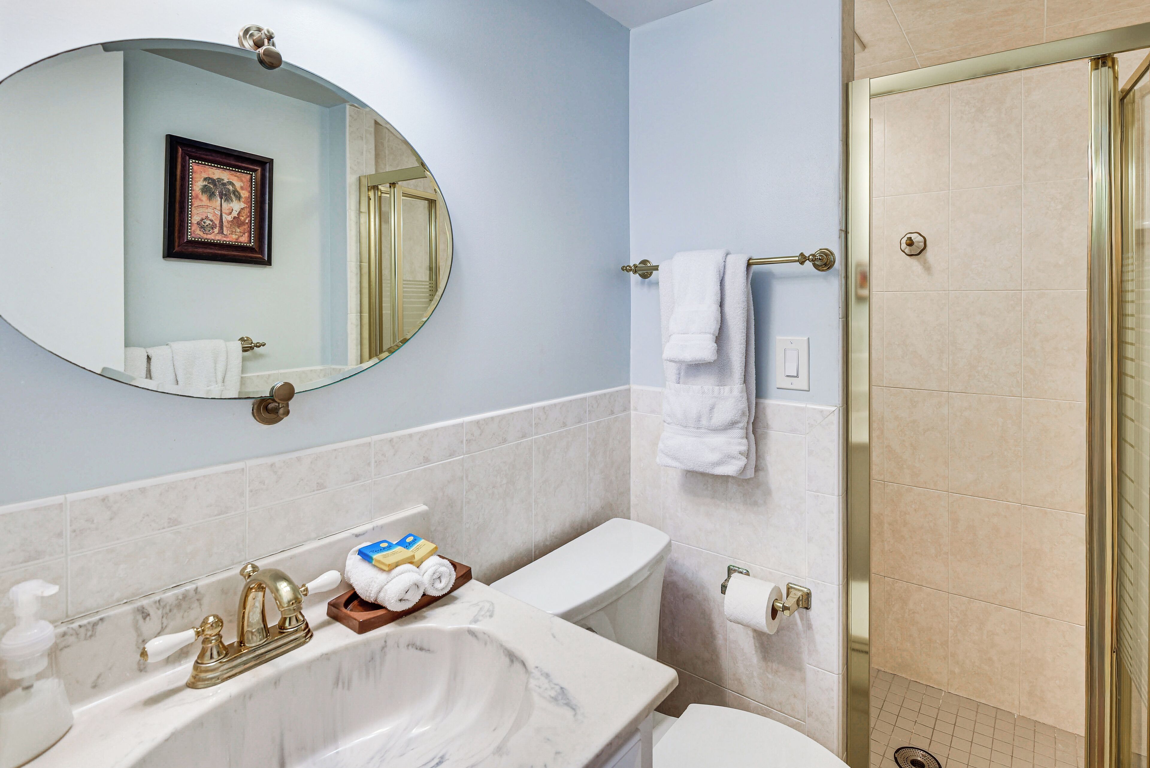A bathroom with a marble sink, a toilet, a shower, and a mirror.