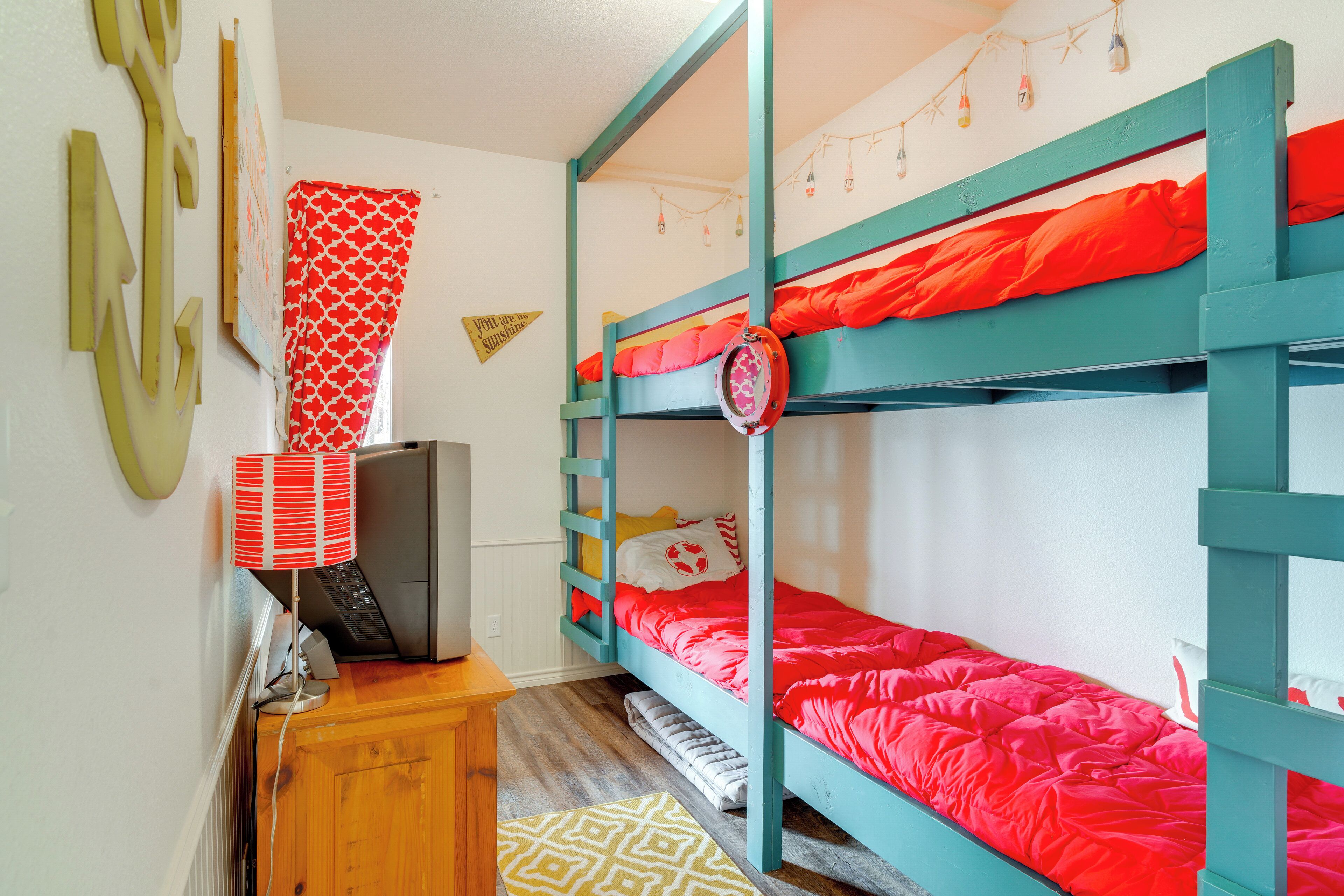 A bunk bed room with a desk, a lamp, and a patterned rug.