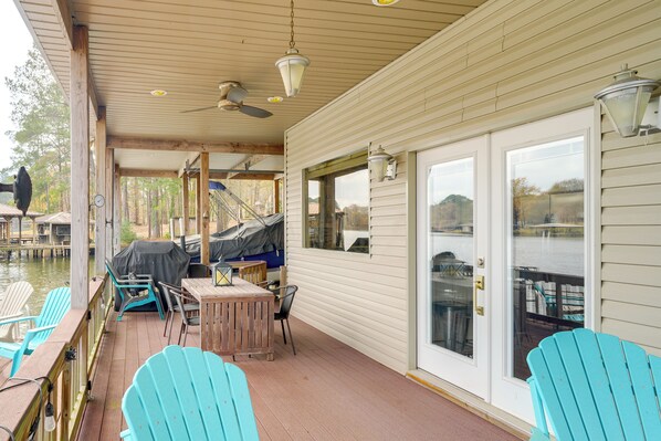 Eine überdachte Terrasse mit Sitzgelegenheiten im Freien, einem überdachten Grill und Blick auf das Wasser.