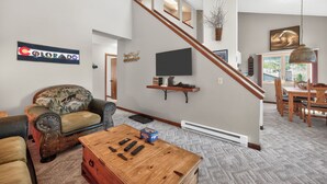 Un salon avec un canapé, une table basse et un téléviseur fixé au mur.