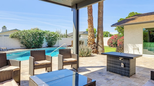 Une terrasse extérieure avec des meubles en osier, une piscine et un espace abrité.