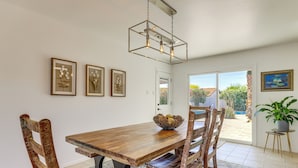 Un espace repas comprenant une table en bois, des chaises, un luminaire suspendu et des œuvres d’art encadrées accrochées aux murs.