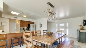 Une cuisine spacieuse avec une table à manger en bois, des tabourets de bar et un luminaire suspendu.