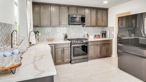 A modern kitchen with grey cabinets, stainless steel appliances, and a herringbone tile backsplash. - 6 Mi to Strip & Chinatown! Poolside Desert Escape (Las Vegas)