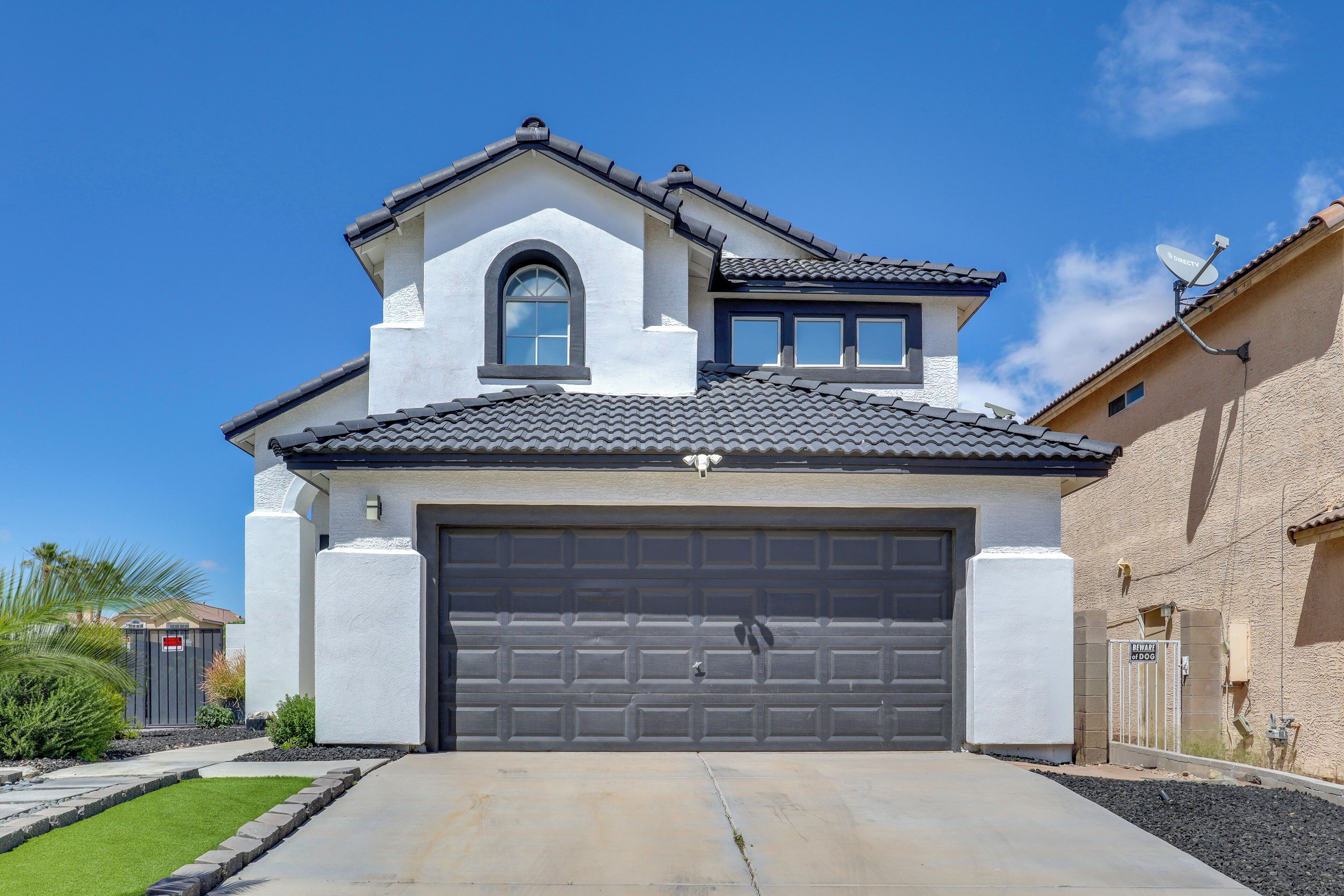 A two-story house with a garage, a satellite dish, and a clear blue sky.