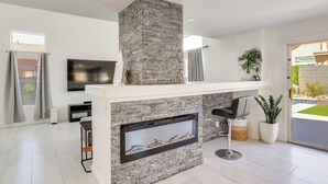 A modern living room with a stone fireplace, a flat-screen TV, and a large window. - 6 Mi to Strip & Chinatown! Poolside Desert Escape (Las Vegas)