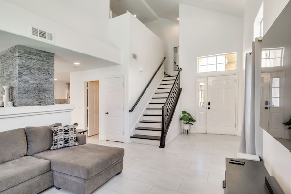A spacious living area with a staircase, a sectional sofa, and a stone accent wall.