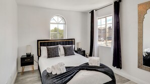 A bedroom with a large bed, a nightstand, a bedside table, a window with curtains, and a mirror on the wall. - 6 Mi to Strip & Chinatown! Poolside Desert Escape (Las Vegas)