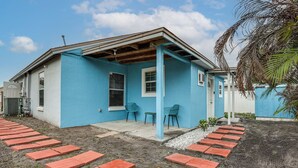 A blue house with a covered porch, a small garden, and a paved walkway. - Private Patio & Yard: East Orlando Extended Stay (Orlando)