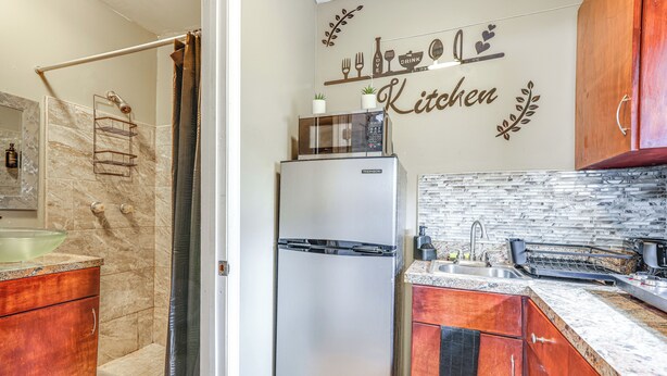 A modern kitchen with a refrigerator, a microwave, and a sink. - Private Patio & Yard: East Orlando Extended Stay (Orlando)