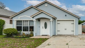 A residential house with a garage, a front door, and a small porch. - Private Patio & Yard: East Orlando Extended Stay (Orlando)