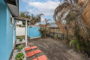 A backyard with a blue shed, a wooden fence, and a palm tree. - Private Patio & Yard: East Orlando Extended Stay (Orlando)