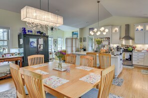 A spacious kitchen with wooden cabinetry, a dining table with chairs, and a chandelier. - Serene Wooded Retreat w/ Patios in Charlottesville (Charlottesville)