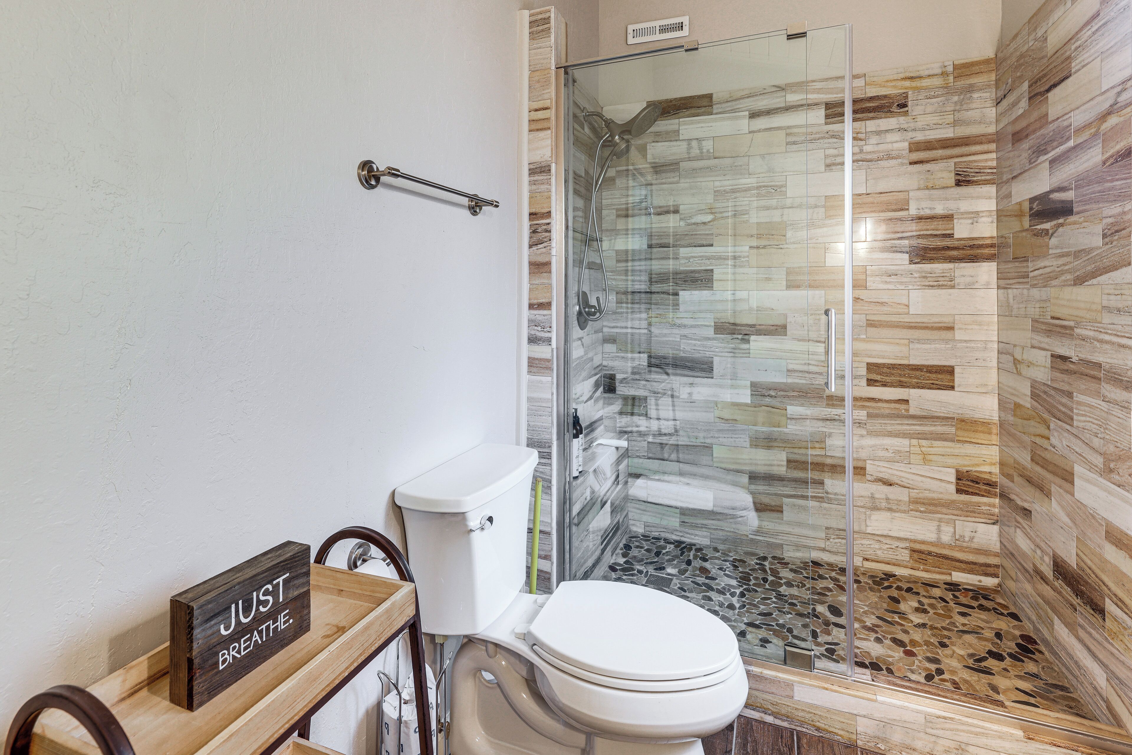 A bathroom with a glass shower enclosure, a toilet, and a wooden vanity.