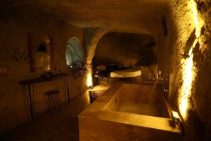 A cave-like interior with a bathtub, a small table, and a mirror.