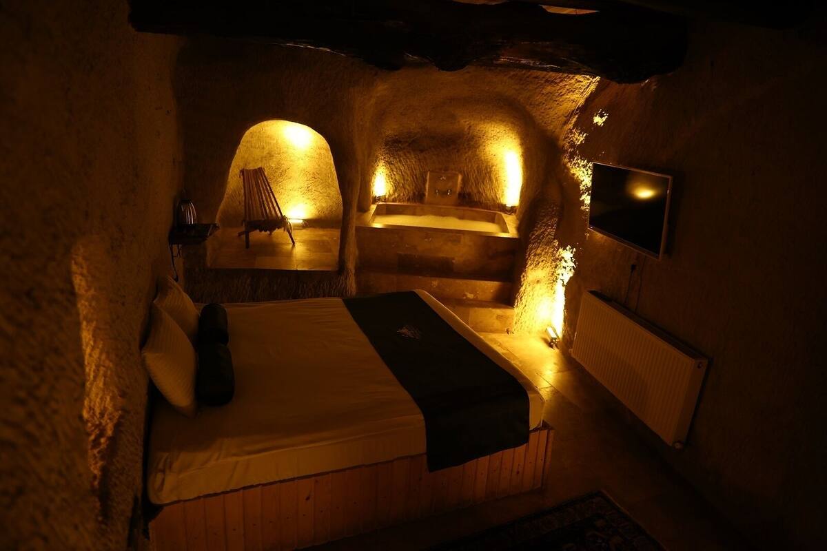 Una habitación acogedora con una cama, una silla, un televisor y una chimenea.