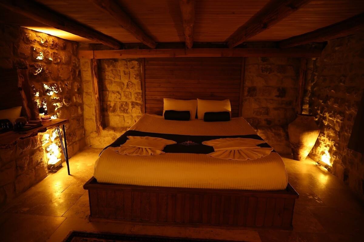 Una habitación acogedora con pared de piedra, una cama de madera y una mesita de noche con lámpara.