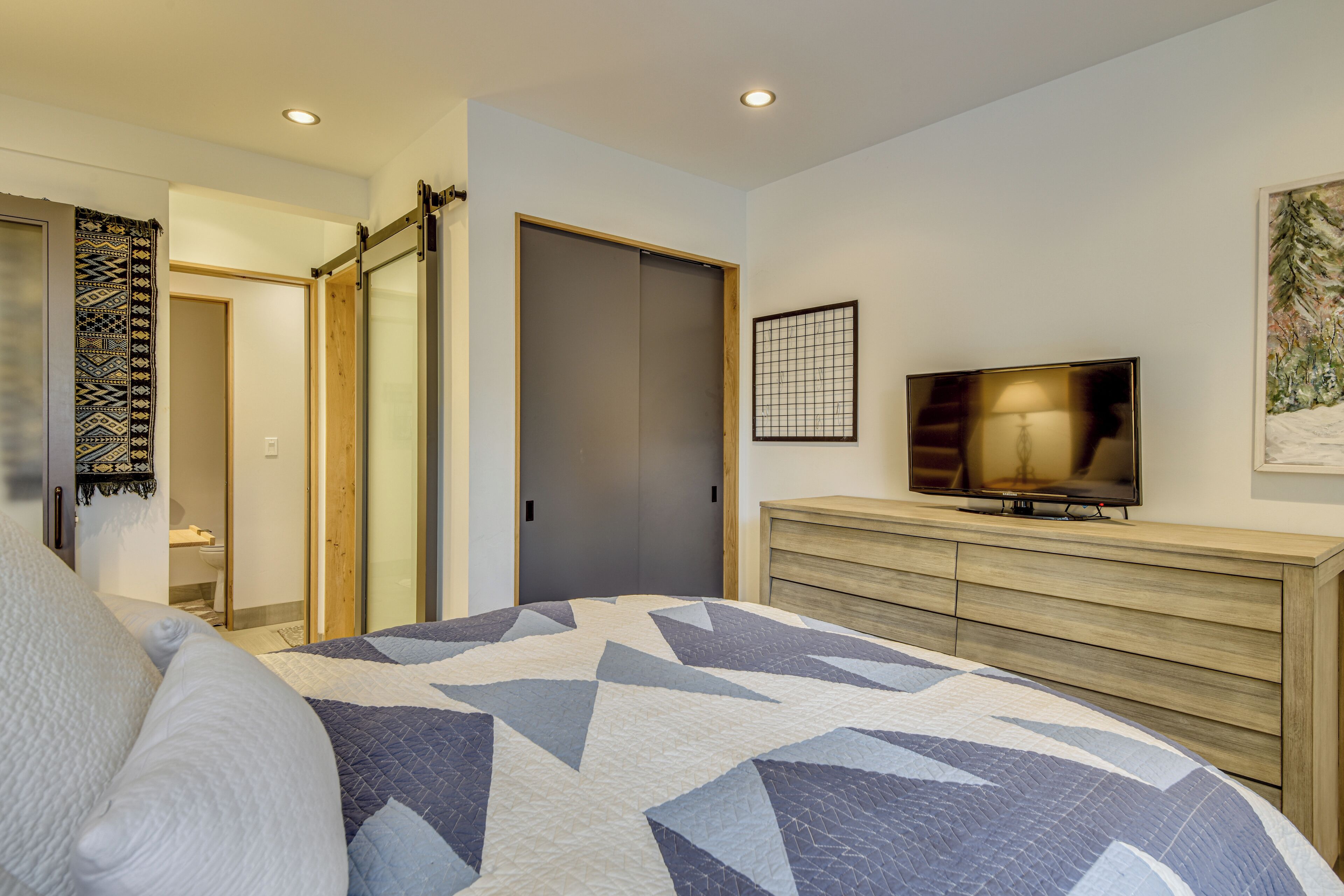 Une chambre à coucher comprenant un lit, une télévision, une commode et une porte coulissante.