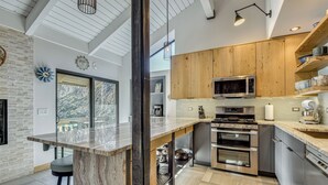 A modern kitchen with wooden cabinets, stainless steel appliances, and a marble countertop. - Walk to Town & Slopes, Views, SPA & Sauna Access (Ketchum)
