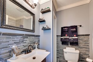 Un baño con un espejo grande, un lavabo blanco, un inodoro y toallas decorativas.