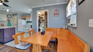 Una cocina con una mesa y un banco de madera, un refrigerador y un microondas.