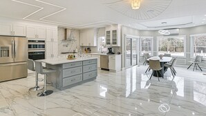 A modern kitchen with marble countertops, stainless steel appliances, and a dining area with a round table and chairs.