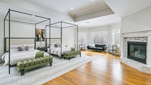 A spacious bedroom with a four-poster bed, a green bench, and a fireplace.