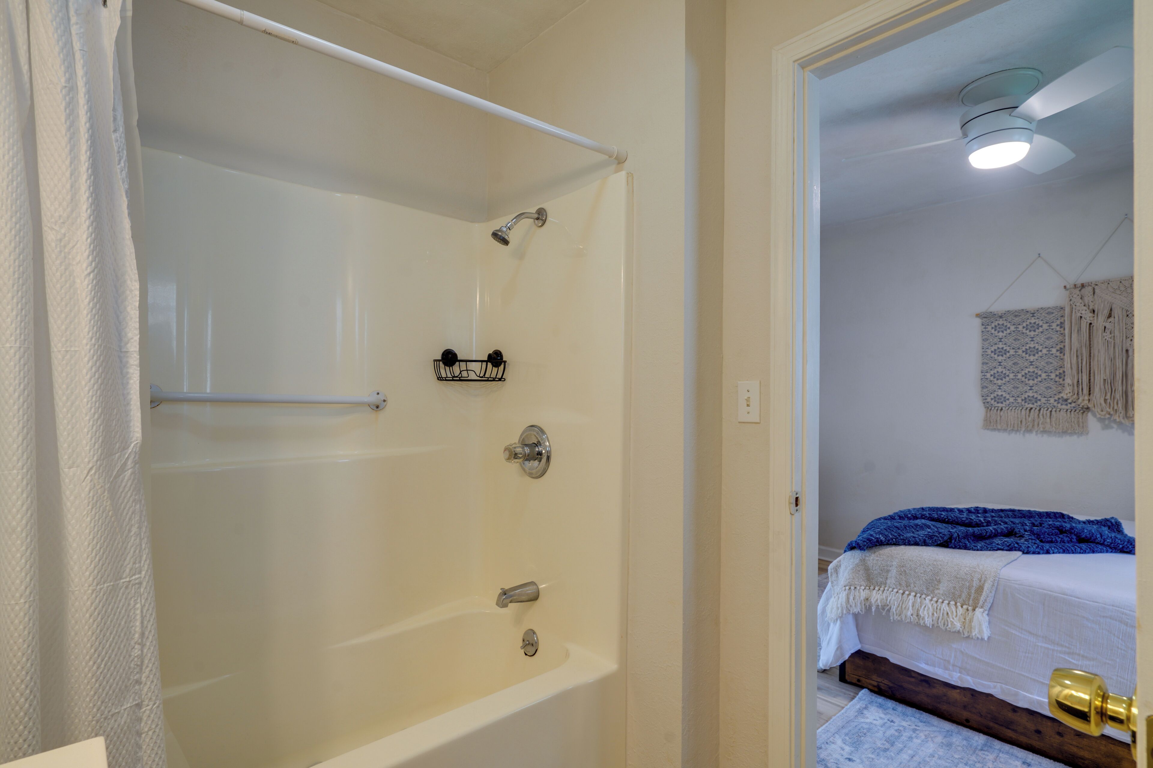Une salle de bain avec une baignoire, une douche et un lit recouvert d’une couverture bleue.
