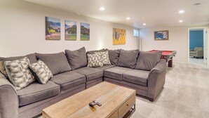 A living room with a sectional sofa, a wooden coffee table, and a pool table. - Hot Tub, Pool Table, Fireplace, Sunny Patio (Arvada)