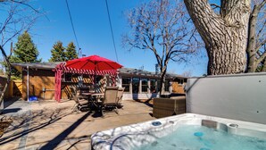 A hot tub with a label, a patio area with chairs and a red umbrella, and a tree. - Hot Tub, Pool Table, Fireplace, Sunny Patio (Arvada)